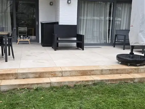 Fertige Terrasse mit Holzstufe am Rasen