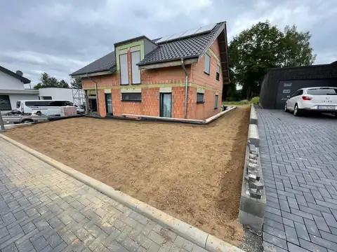 Neue Pflasterfläche und vorbereitetes Beet am Neubau