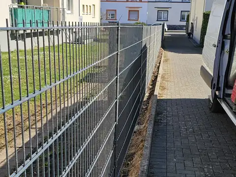 Doppelstabmattenzaun neben gepflastertem Weg