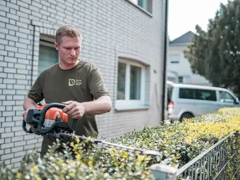 Heckenschnitt mit der Heckenschere vor einem Haus